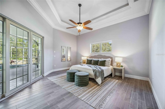 bedroom with hardwood / wood-style floors, a raised ceiling, ceiling fan, access to exterior, and ornamental molding