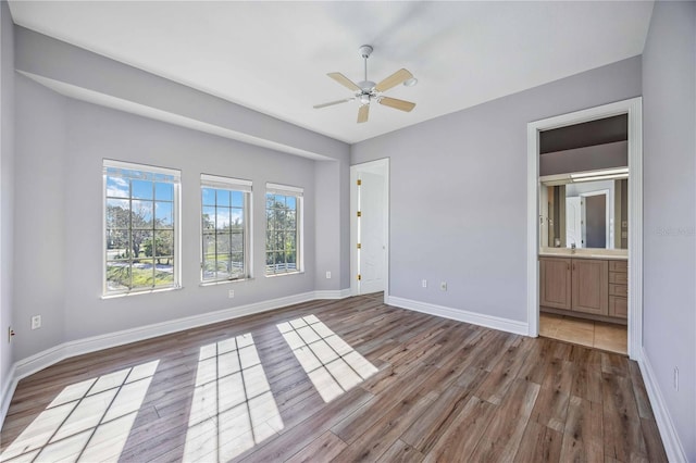 unfurnished bedroom with wood-type flooring, connected bathroom, ceiling fan, and sink