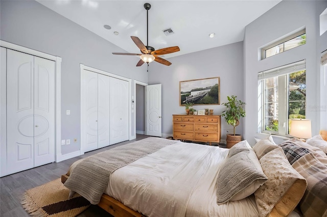 bedroom featuring dark hardwood / wood-style flooring, two closets, ceiling fan, and lofted ceiling