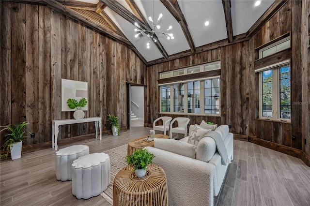 interior space with beamed ceiling, light wood-type flooring, high vaulted ceiling, and an inviting chandelier