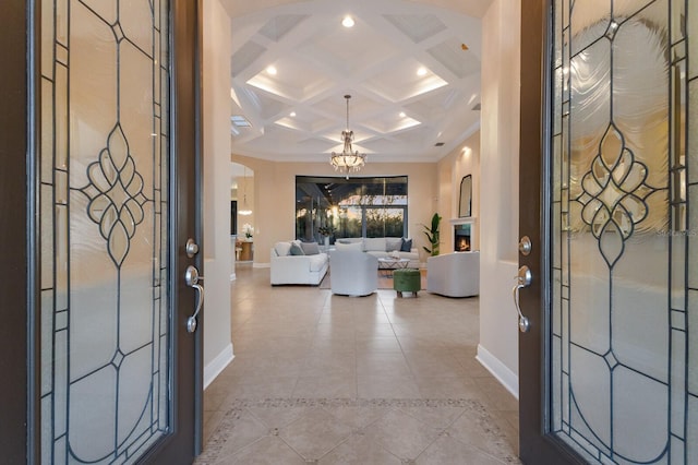 tiled entryway with beamed ceiling, crown molding, coffered ceiling, and a notable chandelier