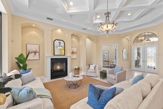 living room featuring beamed ceiling, a chandelier, a high ceiling, coffered ceiling, and french doors