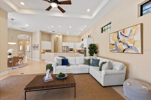 tiled living room with a tray ceiling and ceiling fan