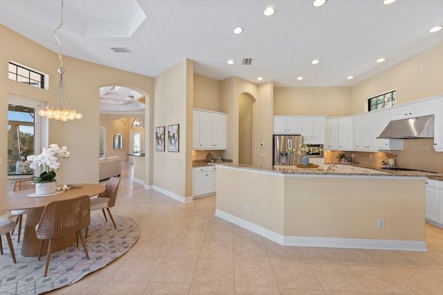 kitchen with a kitchen island, white cabinetry, decorative backsplash, stainless steel fridge with ice dispenser, and light stone countertops