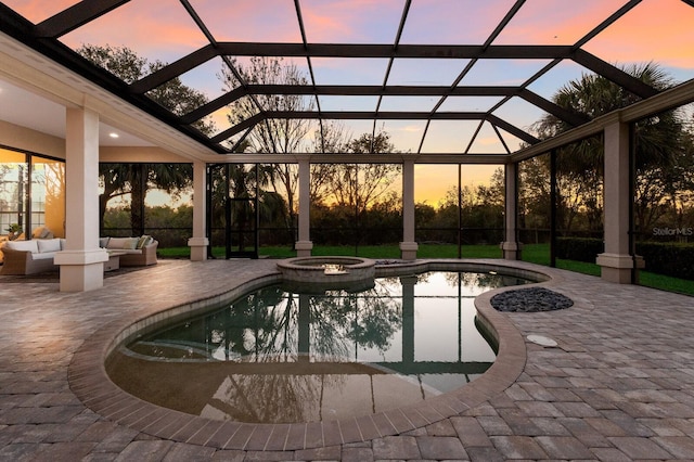 pool at dusk featuring an in ground hot tub, a lanai, an outdoor hangout area, and a patio area