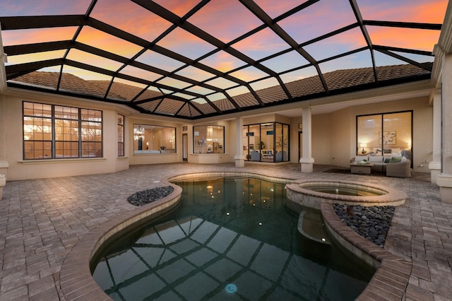 pool at dusk featuring decorative columns and an in ground hot tub