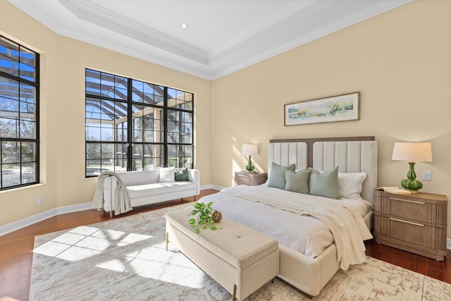 bedroom with multiple windows, crown molding, hardwood / wood-style floors, and a tray ceiling