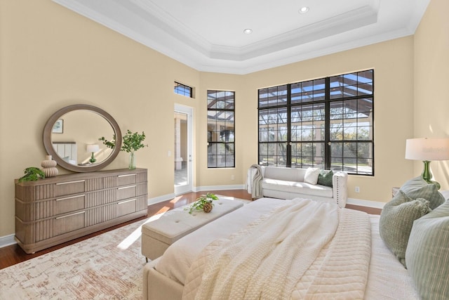 bedroom featuring ornamental molding, wood-type flooring, a tray ceiling, and a towering ceiling