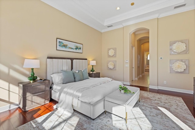 bedroom featuring hardwood / wood-style floors, a tray ceiling, and ornamental molding