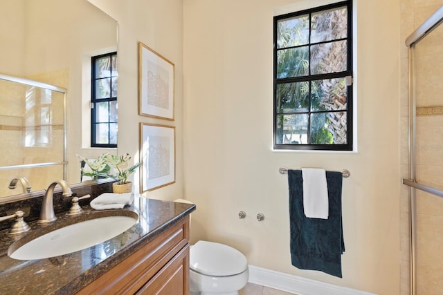 bathroom featuring vanity, a shower with shower door, and toilet