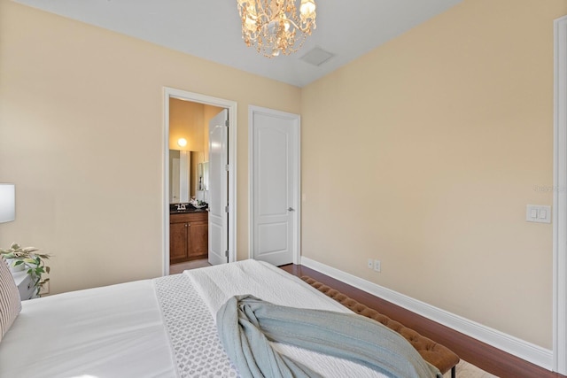 bedroom featuring an inviting chandelier, ensuite bathroom, and dark hardwood / wood-style floors