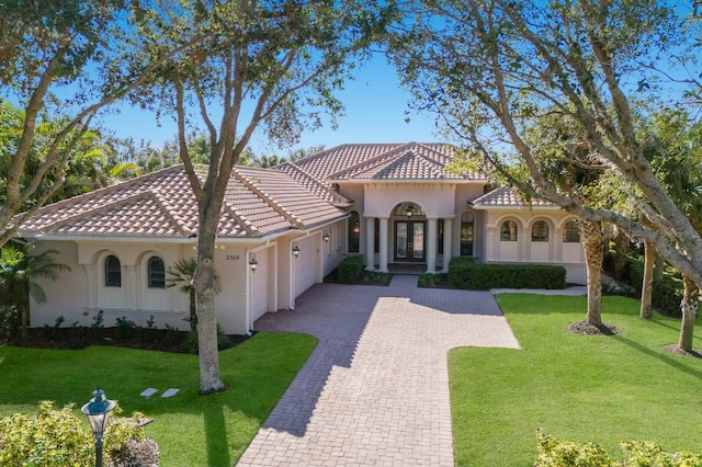 mediterranean / spanish-style home featuring a garage and a front lawn