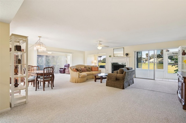 living room featuring carpet, a healthy amount of sunlight, and ceiling fan with notable chandelier