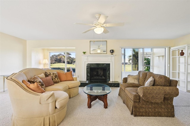 carpeted living room with ceiling fan and a premium fireplace