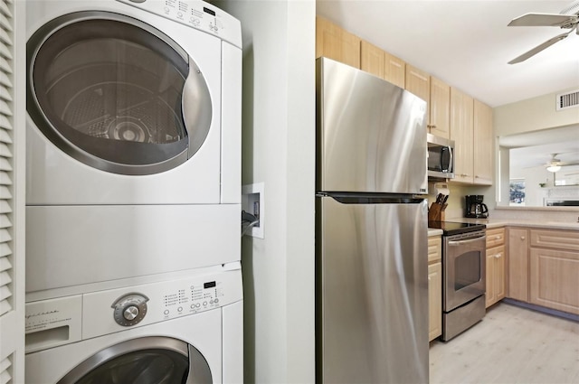 laundry room featuring stacked washer / drying machine, ceiling fan, and light wood-type flooring