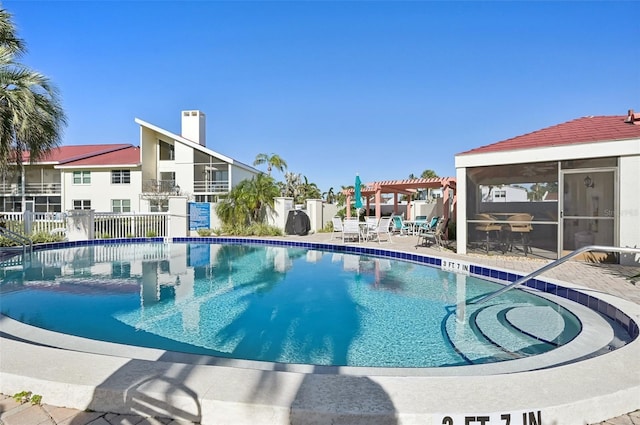 view of pool featuring a pergola, a sunroom, and a patio