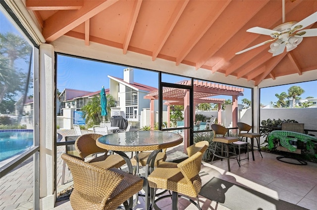 sunroom with a wealth of natural light, vaulted ceiling with beams, and ceiling fan