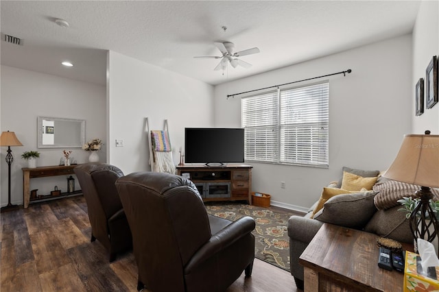 living room featuring ceiling fan, dark wood-type flooring, and a textured ceiling