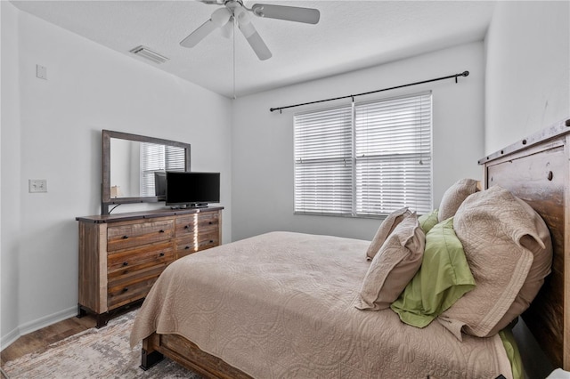 bedroom featuring ceiling fan, wood-type flooring, and multiple windows