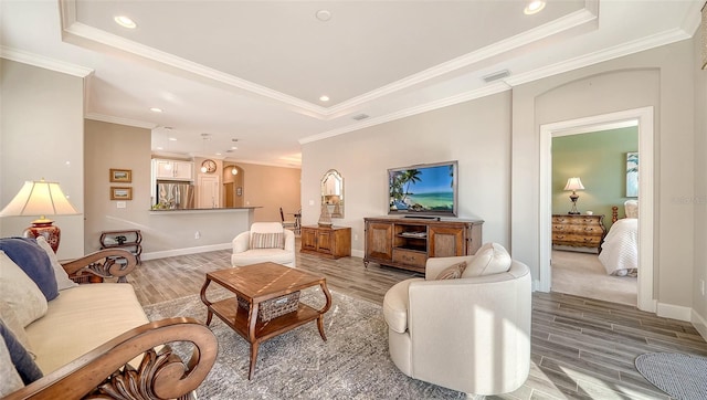 living room with hardwood / wood-style floors, a raised ceiling, and ornamental molding