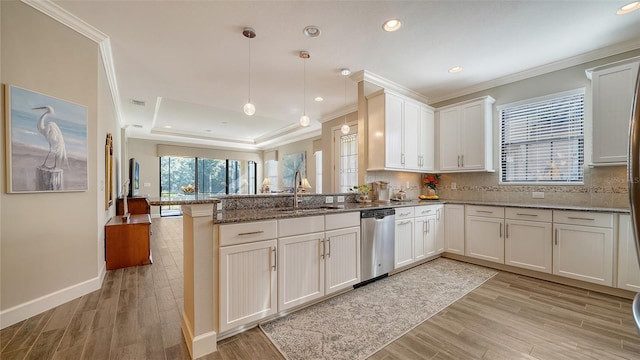 kitchen with sink, stainless steel dishwasher, kitchen peninsula, dark stone countertops, and pendant lighting