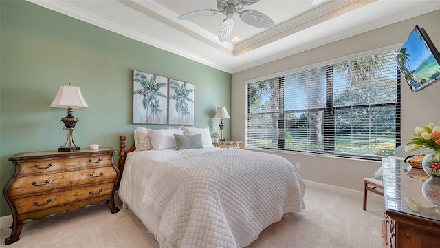 carpeted bedroom with ceiling fan, ornamental molding, and a tray ceiling