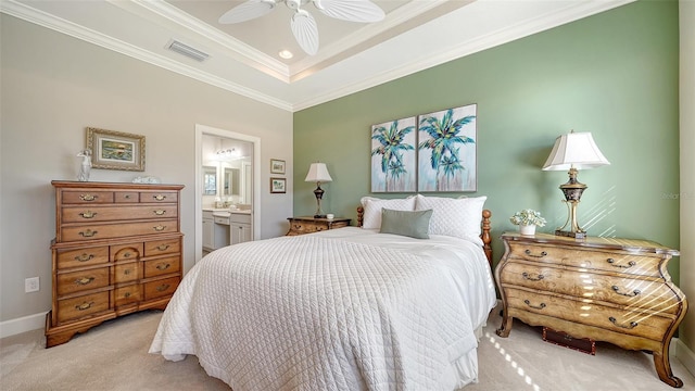 bedroom with light carpet, a raised ceiling, crown molding, ceiling fan, and connected bathroom