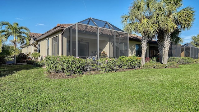 back of house with a lawn and a lanai