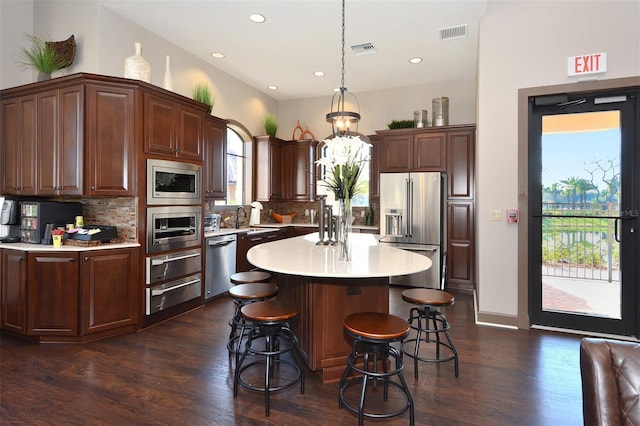 kitchen featuring backsplash, hanging light fixtures, a wealth of natural light, appliances with stainless steel finishes, and a kitchen island