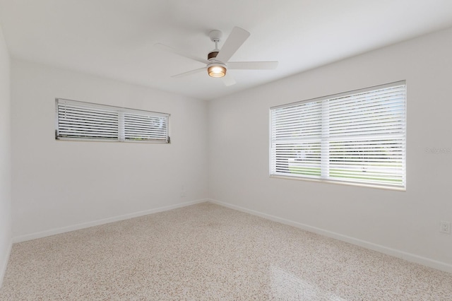 spare room with ceiling fan and baseboards