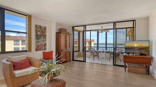 living area with ceiling fan, light hardwood / wood-style flooring, expansive windows, and a healthy amount of sunlight