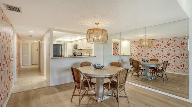 dining space with light wood-type flooring and an inviting chandelier