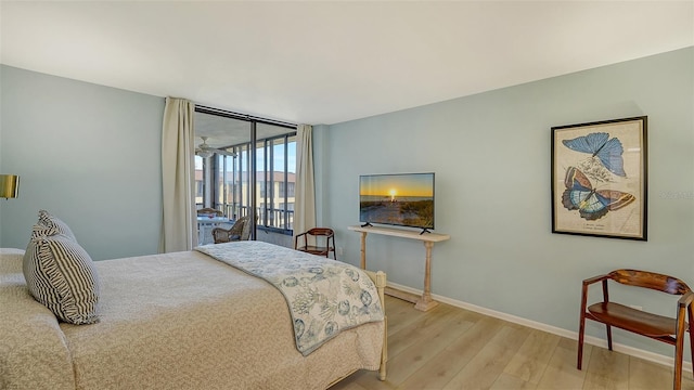 bedroom featuring floor to ceiling windows, light wood-type flooring, and access to outside