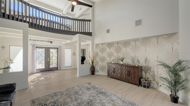 entryway featuring french doors, a towering ceiling, ceiling fan, and beamed ceiling