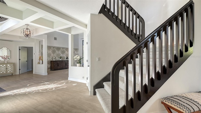 staircase featuring beamed ceiling, coffered ceiling, and a notable chandelier