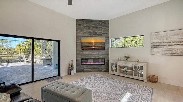 living room with light hardwood / wood-style flooring, a tile fireplace, and ceiling fan