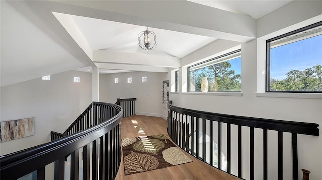 corridor featuring vaulted ceiling, hardwood / wood-style floors, and an inviting chandelier