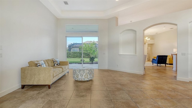 tiled living room with a raised ceiling and a chandelier