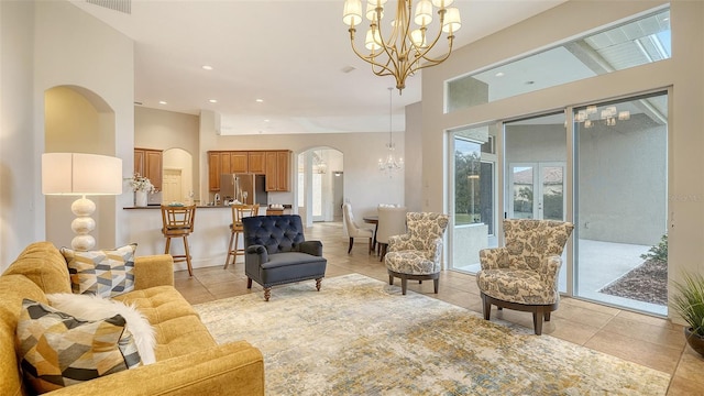 tiled living room featuring a towering ceiling and a notable chandelier