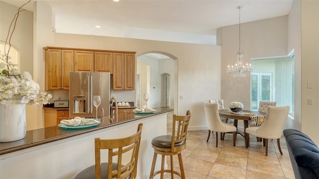 kitchen with high end fridge, a breakfast bar, pendant lighting, light tile patterned floors, and an inviting chandelier