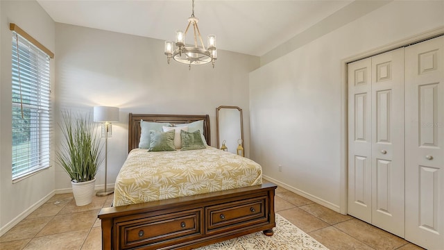 tiled bedroom featuring an inviting chandelier, multiple windows, and a closet