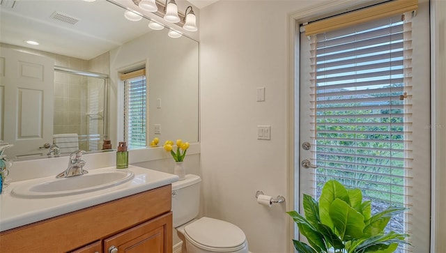 bathroom featuring an enclosed shower, vanity, a healthy amount of sunlight, and toilet