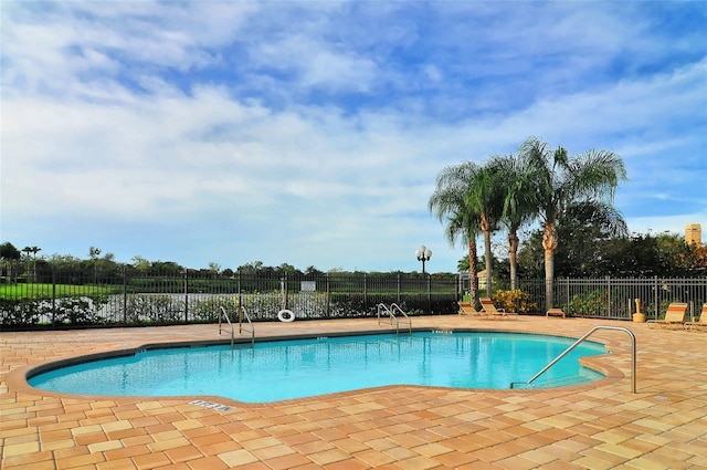 view of swimming pool featuring a water view and a patio area