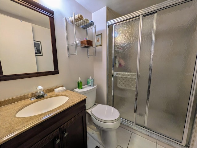 bathroom featuring toilet, vanity, tile patterned floors, and a shower with door