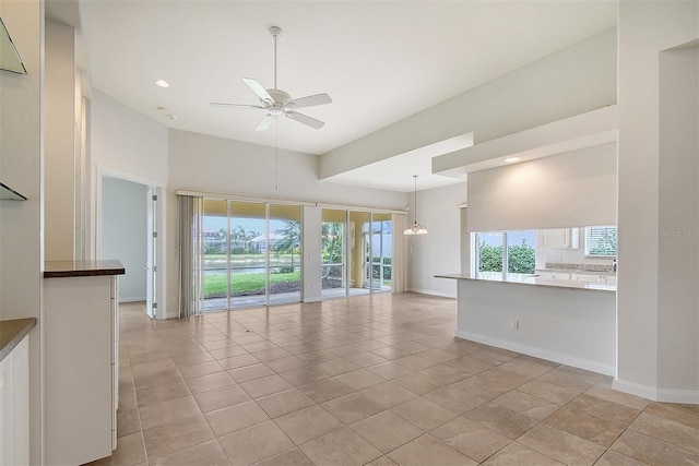 unfurnished living room with ceiling fan with notable chandelier and light tile patterned flooring