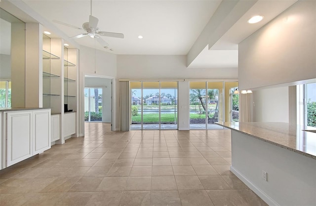 unfurnished living room featuring a wealth of natural light, ceiling fan, built in features, and light tile patterned floors