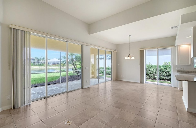 interior space with a water view, light tile patterned floors, and an inviting chandelier