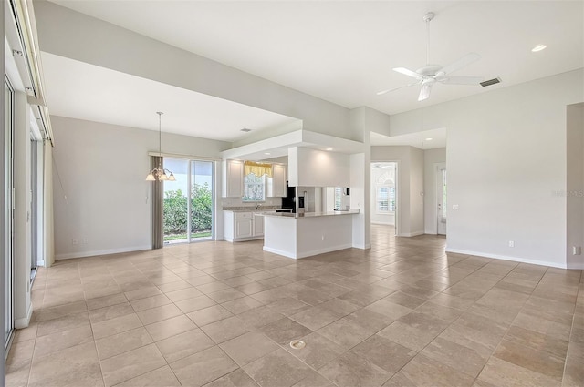 unfurnished living room featuring ceiling fan with notable chandelier