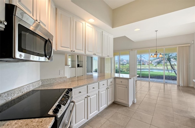 kitchen with stove, light tile patterned floors, decorative light fixtures, and white cabinetry