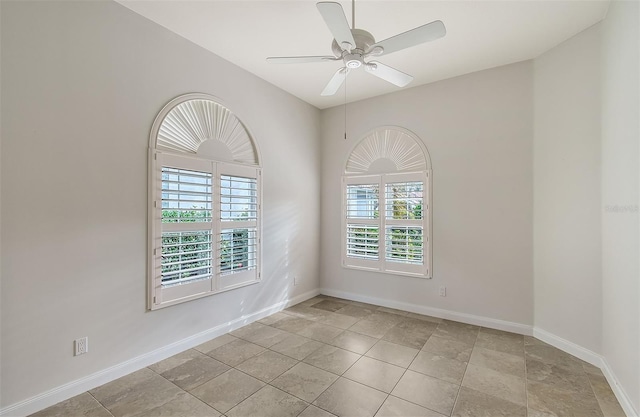 empty room featuring light tile patterned floors, a wealth of natural light, and ceiling fan